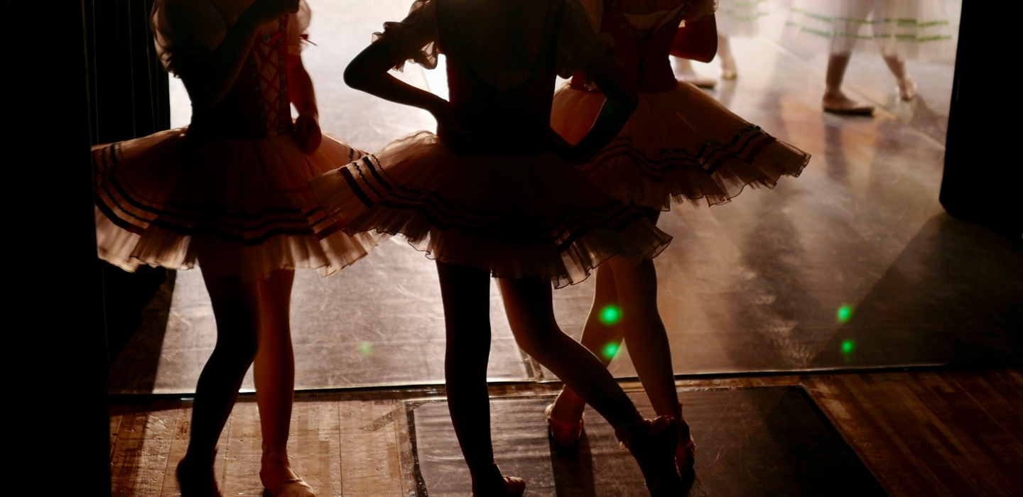 Bildet viser tre unge jenter som danser ballett. De venter på å på på scenen.